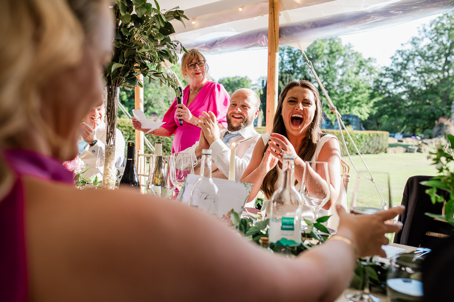 Typical documentary wedding photography moment where bride, groom and mother of the bride are cracking up laughing at a wedding speech.