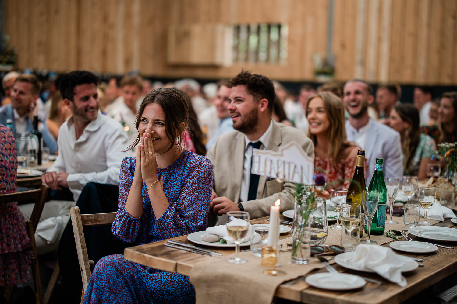 Wedding guests smile at a touching speech during a boho inspired wedding reception at The Grain Store.