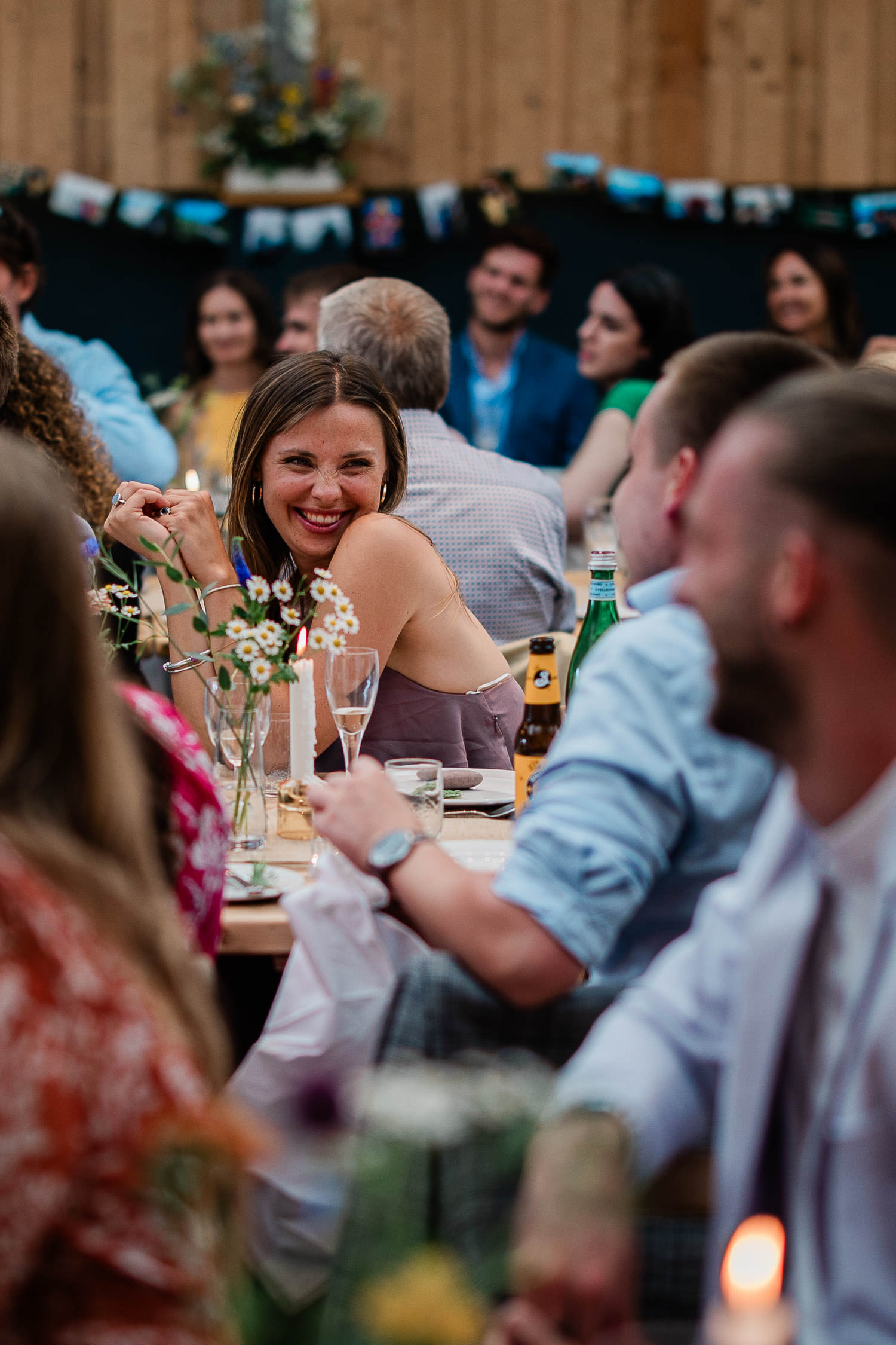 Wedding guest smiling to a friend, during a funny wedding speech.