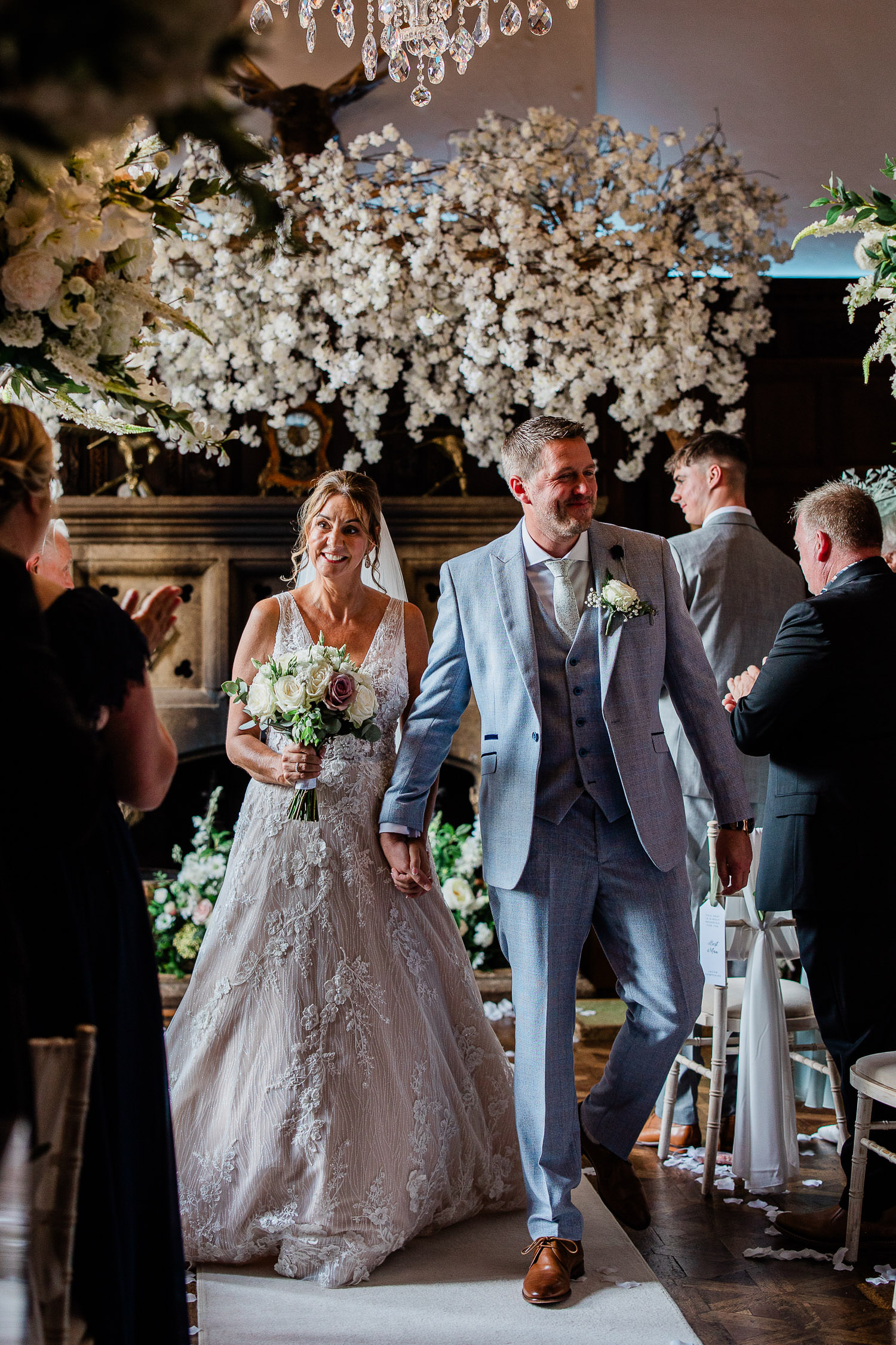 A bride and groom smile at their friends as they walk down the aisle after having been pronounced husband and wife.