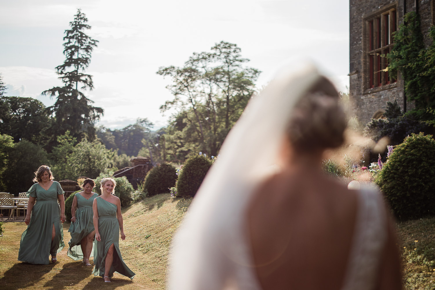 A bride watches her bridesmaids coming towards her, during a wedding portrait session.