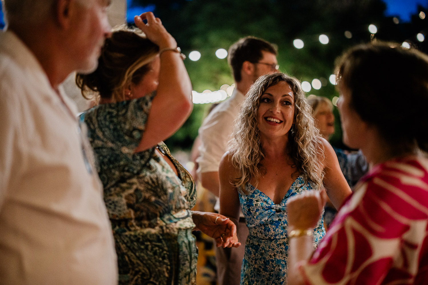 A candid moment of guests smiling and dancing on the dance floor at a wedding in France.