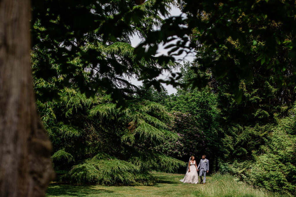 A newly wed couple taking a stroll in the woods, during a documentary style couple portrait session in Devon.