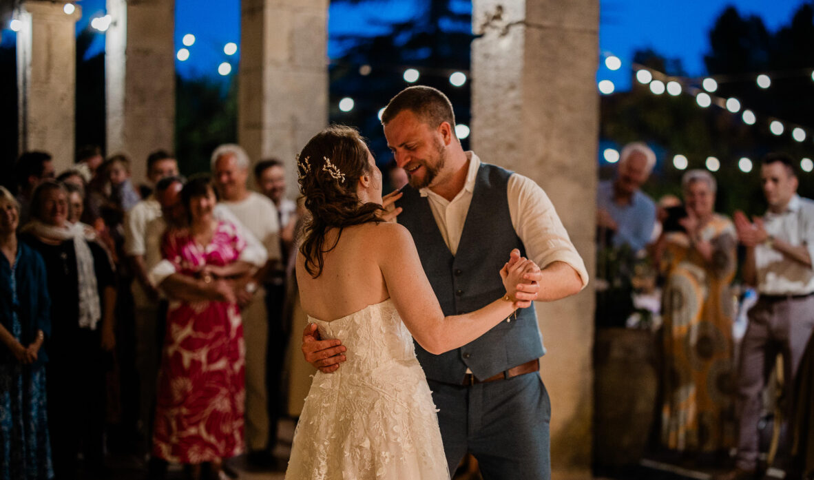 A groom and bride enjoy their romantic first dance at a french chateau, with their friends and family surrounding them.