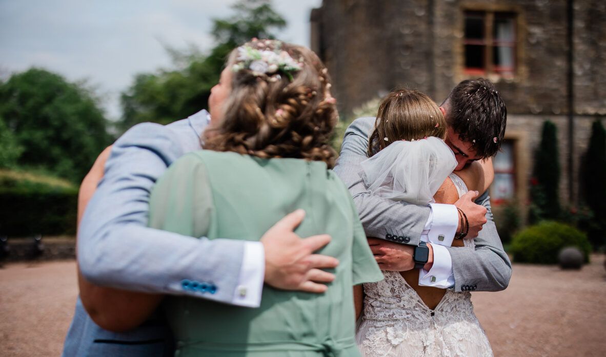 A bride and groom exchange heartfelt hugs with their friends during the wedding reception.