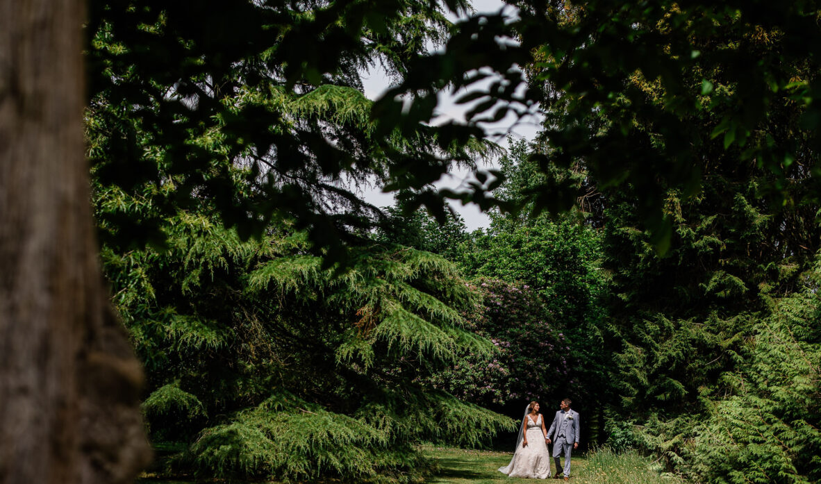 A newly wed couple taking a stroll in the woods, during a Huntsham Court wedding photography session.