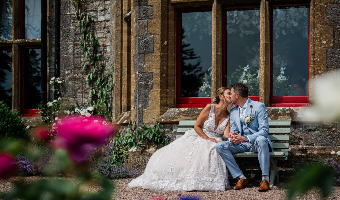 A bride and groom share a tender moment in conversation, sitting in the grounds of a Tudor wedding venue in Somerset.