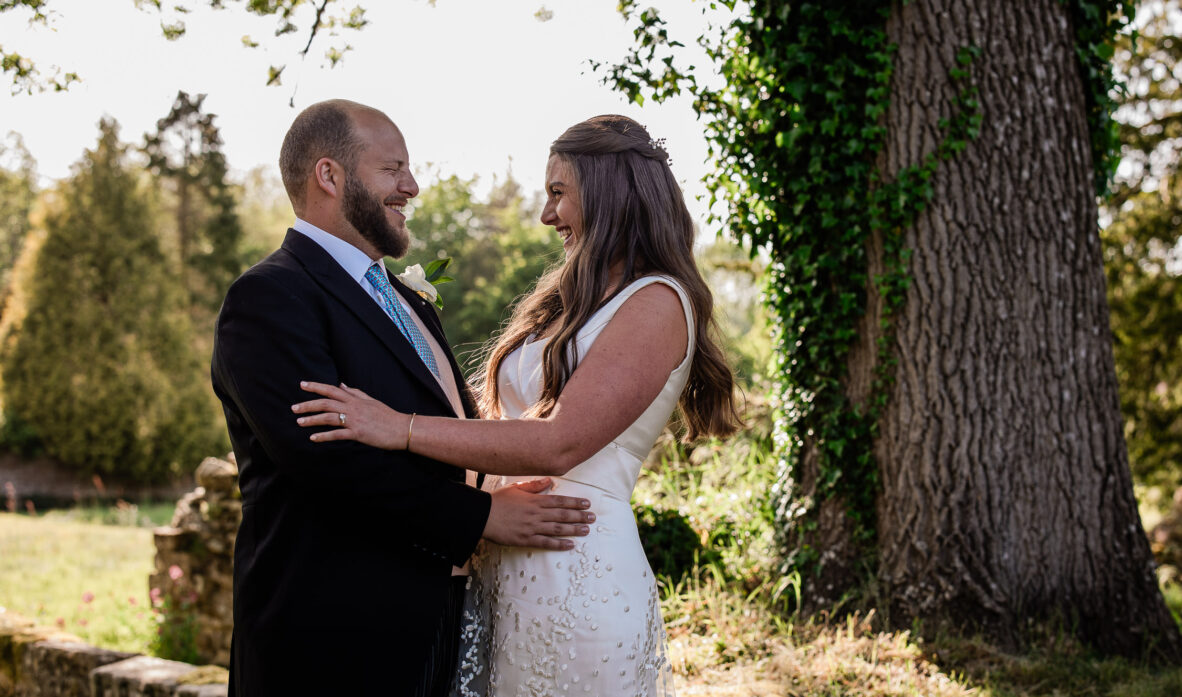 A bride and groom share a laugh during a wedding portrait session at Slaugham Place in Sussex.