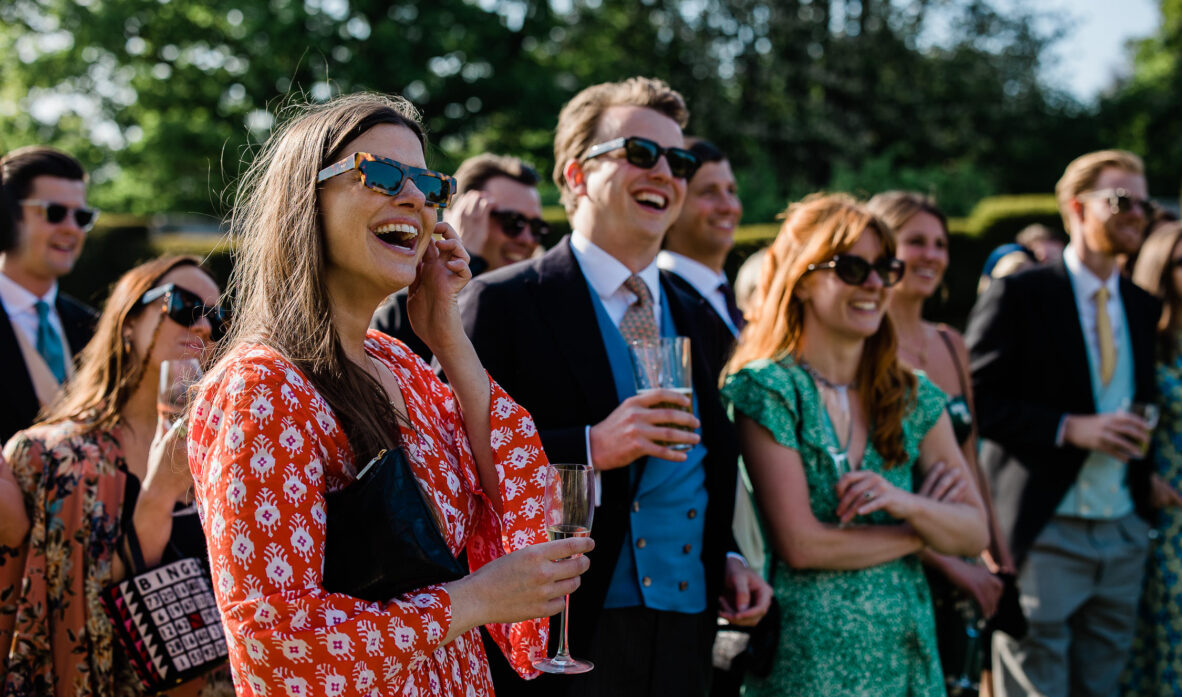 Wedding guests clapping and smiling during outdoor wedding speeches at Slaugham Place.