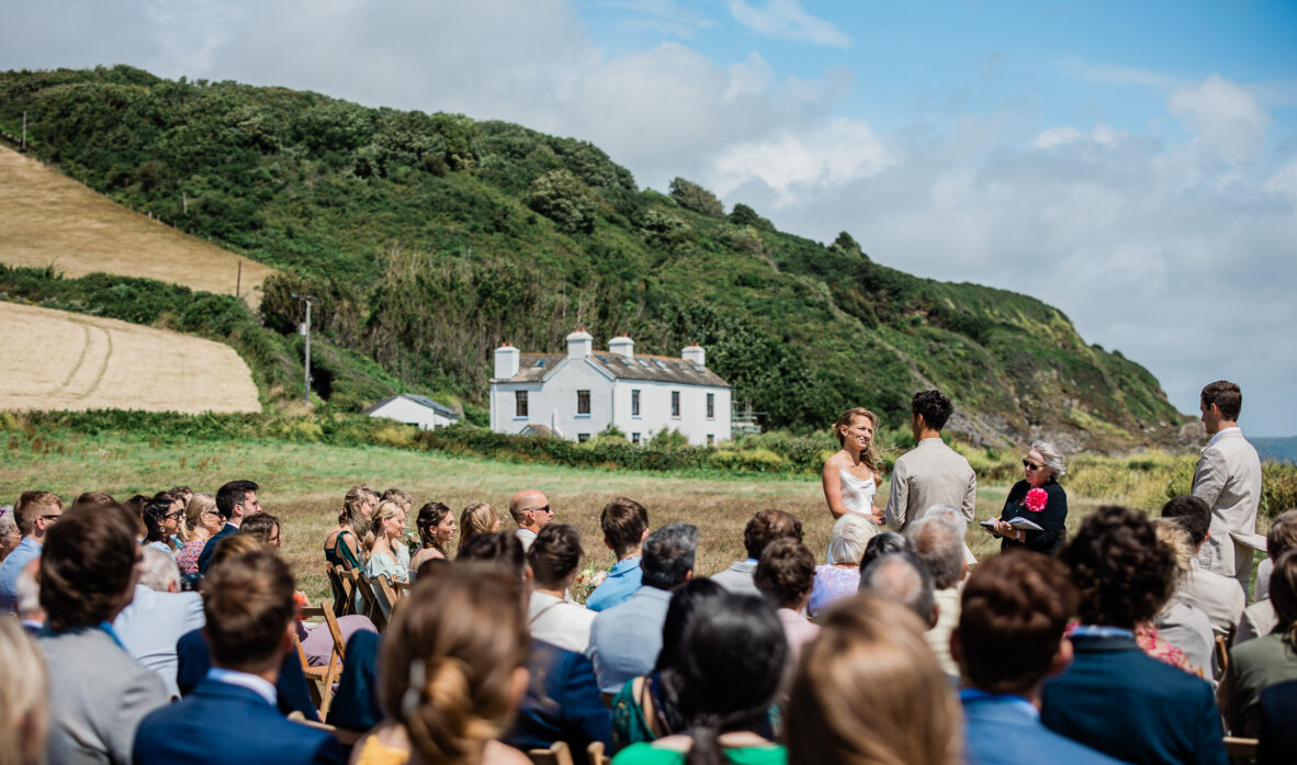 A bride and groom exchange their vows outside, by the sea.