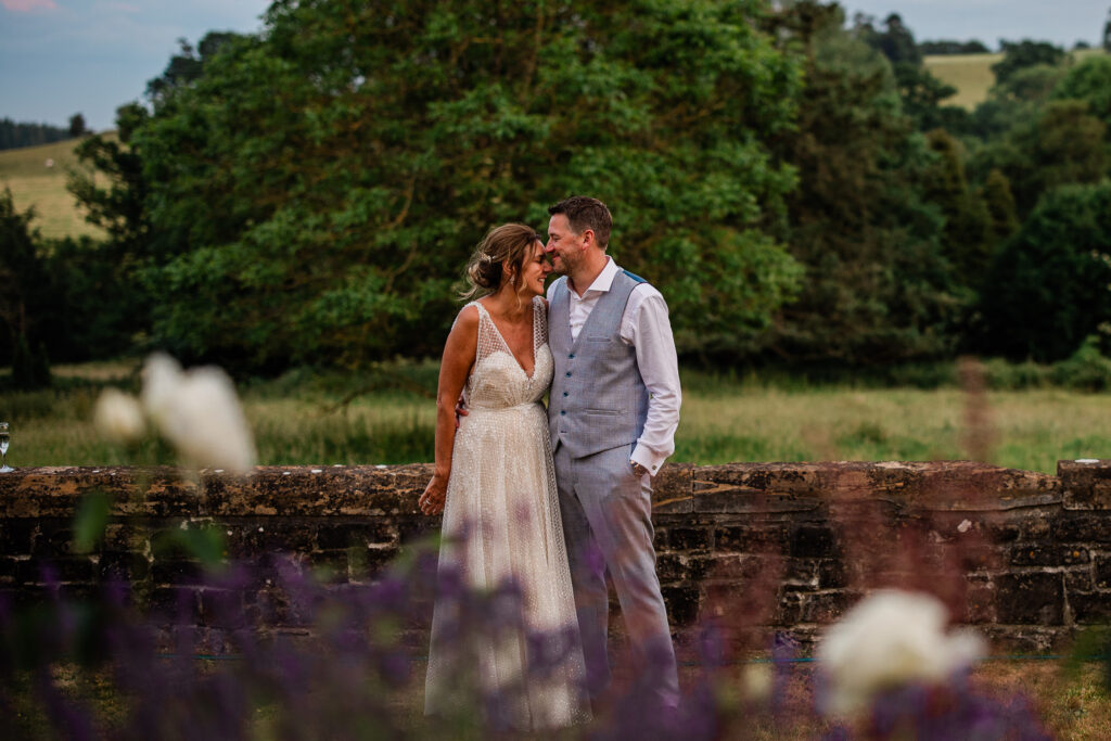 A bride and groom have an intimate moment in the terraced gardens of Huntsham Court, at sunset.