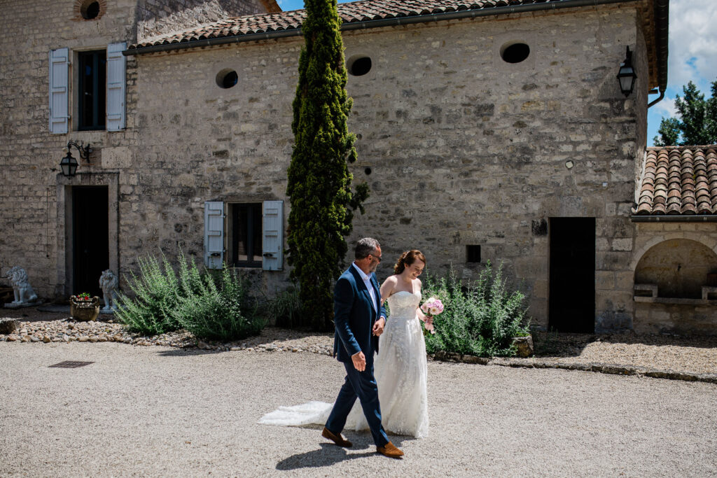 A bride walks to the ceremony on her father's arm, at a destination wedding in Toulouse, France.