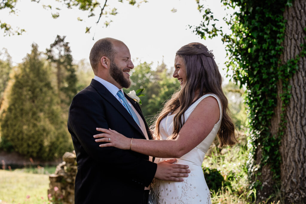 A bride and groom share a laugh during a wedding portrait session at Slaugham Place in Sussex.